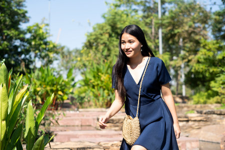 Long hair woman in dark blue dress is very excited that she will meet her boyfriend, she herry walking to the appointment place in the park.の写真素材