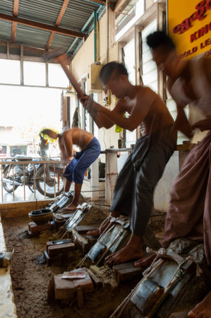 Young craftsman punching gold in the traditional way to make leaf gold. in Mandalay, Myanmarのeditorial素材