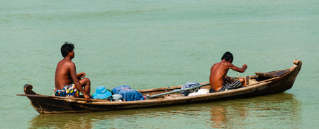 Two Asian men rowing wooden boat on a river in Burma, Myanmarのeditorial素材