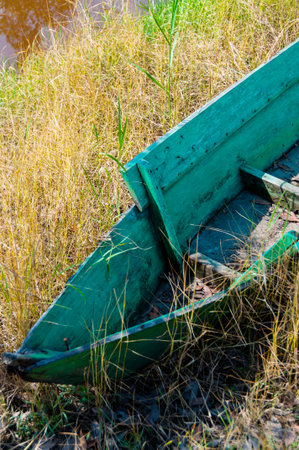 Abandoned front of an empty wooden Boat laying in the grasの写真素材