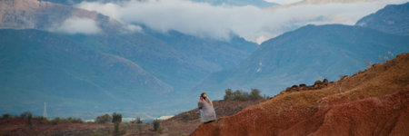 Woman sitting on big red sandstone rock formation slope in hot dry desert of Tatacoa, Huila, Colombiaの写真素材