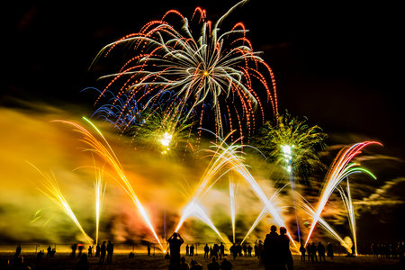 Colorful fireworks of various colors over night sky with spectatorsの写真素材