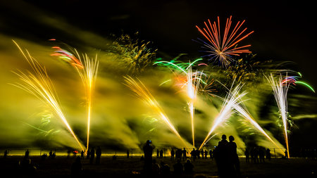 Colorful fireworks of various colors over night sky with spectatorsの写真素材