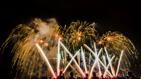 Colorful fireworks of various colors over night sky with spectatorsの写真素材