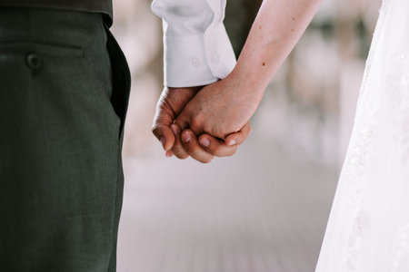 Bride and groom in grey pants and white shirt holding hands while walkingの写真素材