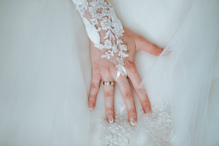 Bride's hand on her wedding dress with the ring and decorated nailsの写真素材