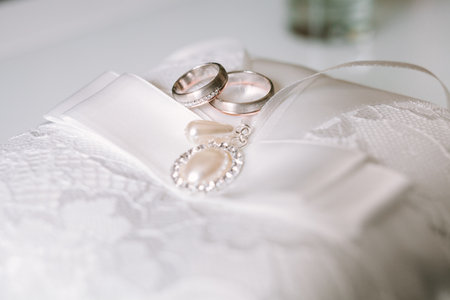 Golden wedding rings close up on white pillowの写真素材