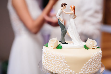 Bride and groom marzipan figures on the wedding cake with white rose decorationの写真素材