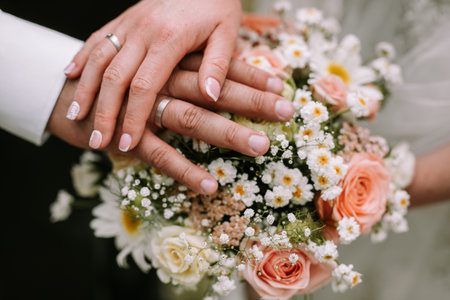 Bride and groom holding hand on the bouquet with pink roses showing the golden ringの写真素材