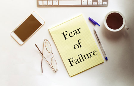 Fear of Failure text on the yellow paper with phone, coffee, penの写真素材