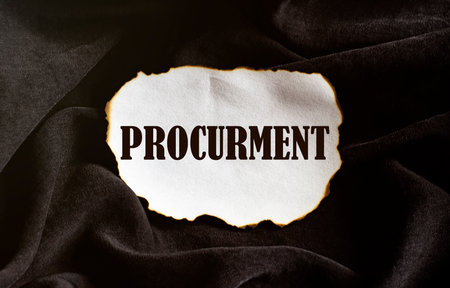 burnt white piece of paper with text Procurment on a black fabric backgroundの写真素材