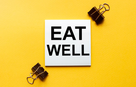 white paper with text Eat Well on a yellow background with stationeryの写真素材