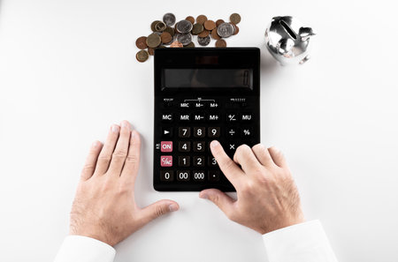 businessman counts his finances into a calculator. coins were also accumulating on the table.の写真素材