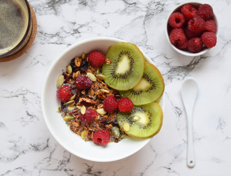 Home made granola with chia, kiwi and raspberries on white marble backgroundの写真素材