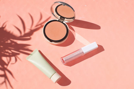 Female accessories Face powder Foundation Blush Highlighter Lipstick Make up Summer holiday concept Flat lay Top view Copy space Tropical leaf shadowYellow background Beautiful compositionの写真素材