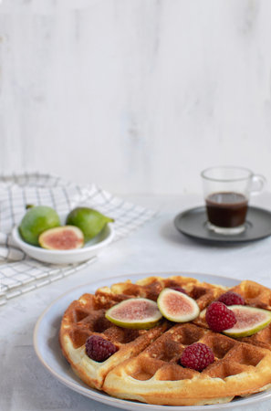 Selective focus Belgian waffles Slow food breakfast concept figs raspberries honey Espresso coffee Checkere napkin white wooden background Horizontal Persperctiveの写真素材