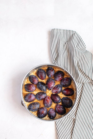 Autumn baking concept - Uncooked Plum piein metal mold on Crumpled Striped Napkin. Top view, Flat lay, Copy space. Minimal picture.の写真素材