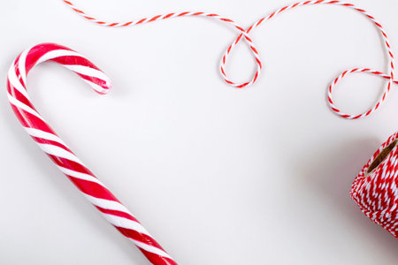 Christmas or New Year concept - Candy canes and twisted red and white cord. White background, top...