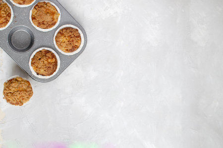 Homemade baking - fresh baked apple muffins on cooling rack, spiced butter in wooden bowl, white background, top view, copy space.の写真素材