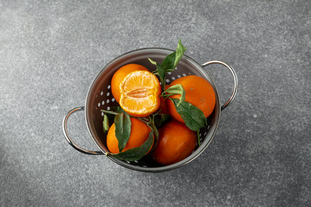 Fresh ripe tangerines in gray colander on textured concrete gray background, top viewの写真素材