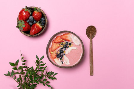 Spring diet, body detox, healthy breakfast concept, lifestyle blog - coconut bowl with fruit smoothie, fresh strawberries, blueberries, coconut chips, top view, pink backgroundの写真素材