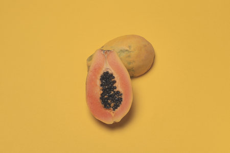 Seasonal tropical fruit, local market half fresh ripe papaya on yellow background, top view, flat lay, copy space, toned imageの写真素材