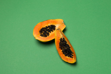 Seasonal tropical fruit, local market half fresh ripe papaya on green background, top view, flat...