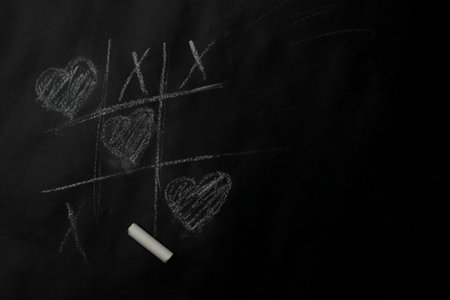 Valentines day minimal concept - tic tac toe game with hearts on chalkboard, copy spaceの写真素材