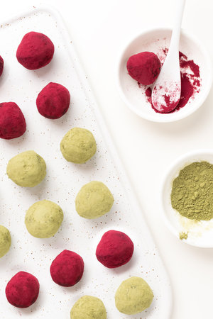 Selective focus on matcha green tea and pink raspberry beetroot truffles close up, white background, copy space - gourmet healthy dessert, top viewの写真素材
