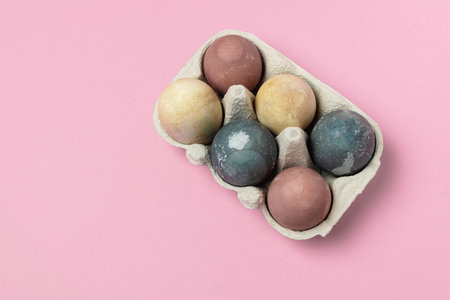 Easter celebration minimal - selective focus of natural coloured easter eggs with curcuma, beetroot, hibiscus tea, quail eggs in cardboard container, pink bacground, rustic styleの写真素材