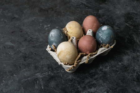 Spring easter minimal rustic style concept - organic naturally dyed easter eggs, qual eggs, curcuma, beetroot, hibiscus tea pigments in cardboard container, gray background, low key photoの写真素材