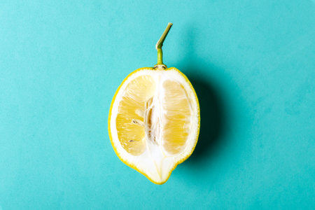 Half of ripe lemon on blue background, top view, minimal composition, summer fruit concept, flat...