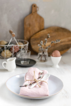 Easter table setting idea, minimal decoration - pink napkin, fork, coloured eggs in white basket,...