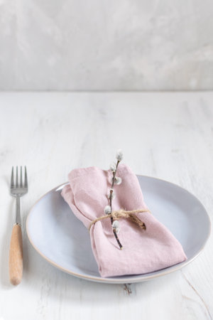 Easter table setting idea, minimal decoration - pink napkin, fork, willow banch, white wooden table, top viewの写真素材