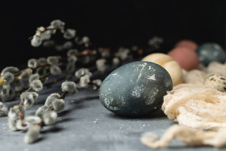 Spring easter minimal rustic style concept - organic naturally dyed easter eggs, qual eggs, curcuma, beetroot, hibiscus tea pigments, willow banch, gray background, low key photoの写真素材