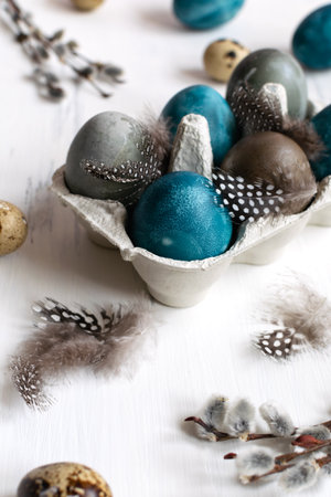 Spring organic easter concept, - naturally dyed easter eggs, quail eggs, feathers, white wooden background, copy spaceの写真素材