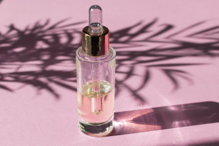 Beauty skincare concept template - dropper glass bottle with cosmetic oil or serum, natural hard light, deep shadows, light pink background, copy spaceの写真素材