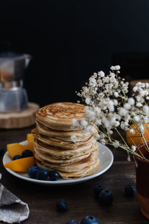 Beautiful served rustic breakfast - stack of american pancakes with blueberries, peach, Gypsophila...