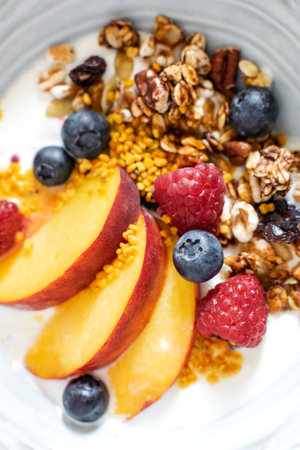 Top view selective focus of granola with greek yogurt fresh peach, blueberry, raspberry on the table - healthy breakfast conceptの写真素材