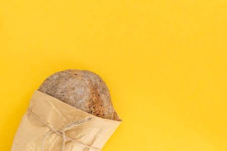 Fresh baked organic whole grain rye bread on bright yellow background, top view, copy spaceの写真素材