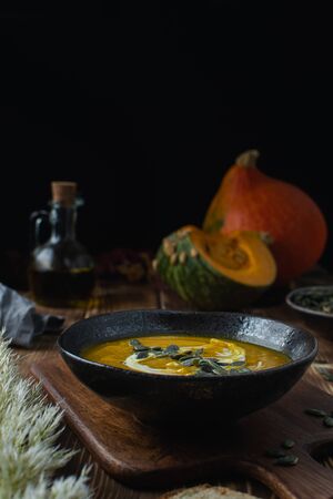 Pumpkin squash soup with seeds, olive oil on dark rustic wooden background, thanksgiving foodの写真素材