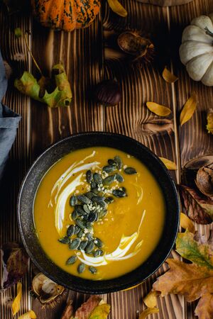 Pumpkin squash soup with seeds, olive oil on dark rustic wooden background, thanksgiving foodの写真素材