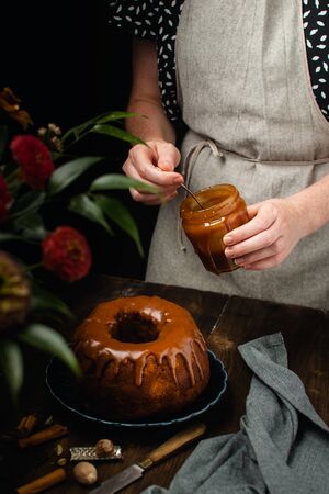 Bund cake with spices, cinnamon, star anise, nutmeg and caramel sauce glaze on dark wooden table, copy spaceの写真素材