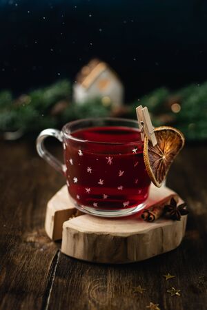 Cup of mulled wine in transparent mug, dried orange, cinnamon stick, star anise on dark bokeh backgroundの写真素材