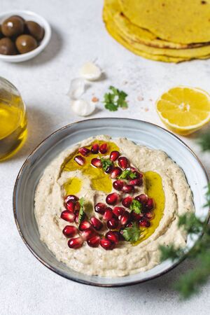 Close up of traditional arabic dip from baked eggplants with olive oil and pomegranate, white tableの写真素材