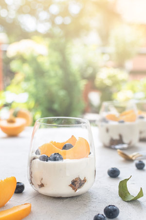 Individual layered desserts with sponge cake, cream and peach fruit, blueberry, trifle, cheesecake,...