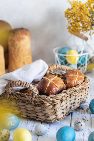 Traditional easter Hot cross buns served in wicker tray, colored eggs