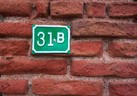 Green number table on a red brick wallの写真素材