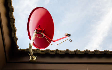 Red satellite dish on the ground outside the house の写真素材