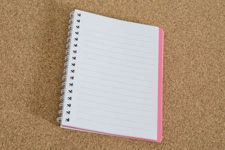 Blank spiral notebook pink on cork board background.の写真素材